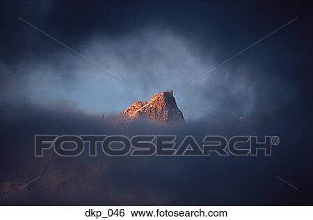 View of a mountain peak through clouds View Large Photo Image Stock Photograph - View of a mountain peak through clouds. Fotosearch