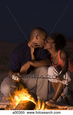 Stock Photography - Young couple kissing by a campfire. Fotosearch