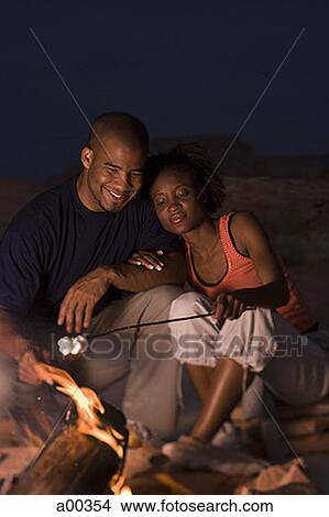 Young couple sitting by a campfire View Large Photo Image Picture - Young couple sitting by a campfire. Fotosearch