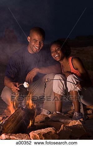 Young couple sitting by a campfire View Large Photo Image Stock Image - Young couple sitting by a campfire. Fotosearch