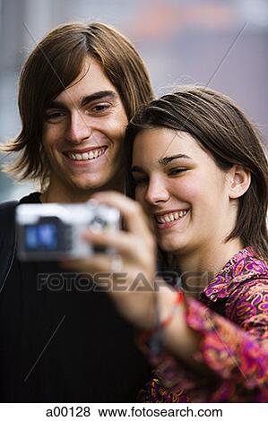 Young couple taking a photograph of themselves View Large Photo Image Stock Photo - Young couple taking a photograph of themselves. Fotosearch