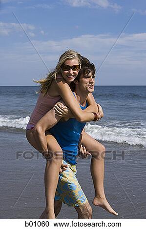 Young man carrying a young woman on his back View Large Photo Image Stock Image - Young man carrying a young woman on his back. Fotosearch