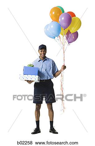 Young man carrying gift boxes while holding balloons View Large Photo Image Stock Photo - Young man carrying gift boxes while holding balloons. Fotosearch
