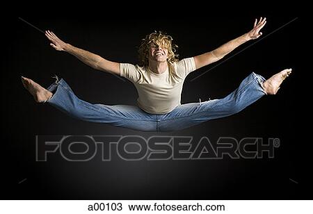 Stock Image - Young man doing splits in mid-air. Fotosearch