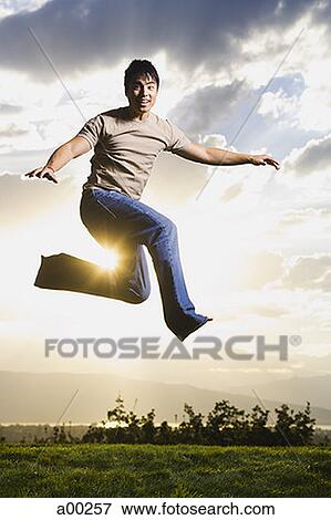 Young man jumping on grass View Large Photo Image Stock Photo - Young man jumping on grass. Fotosearch