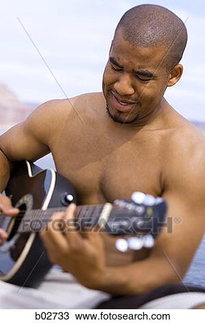 Young man playing a guitar View Large Photo Image Stock Image - Young man playing a guitar. Fotosearch
