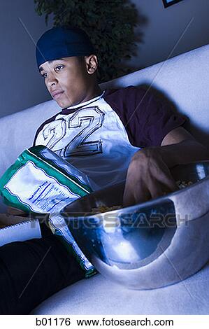 Stock Photograph - Young man sitting on a couch. Fotosearch