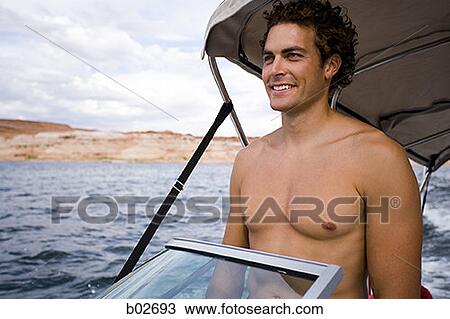 Young man standing on a speed boat View Large Photo Image Stock Image - Young man standing on a speed boat. Fotosearch
