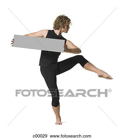 Young man standing on one leg and holding a blank sign View Large Photo Image Stock Photo - Young man standing on one leg and holding a blank sign. Fotosearch