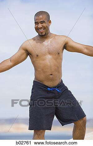 Young man standing with his arm outstretched View Large Photo Image Stock Image - Young man standing with his arm outstretched. Fotosearch