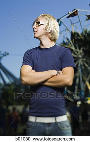 Young man standing with his arms crossed View Large Photo Image Stock Image - Young man standing with his arms crossed. Fotosearch