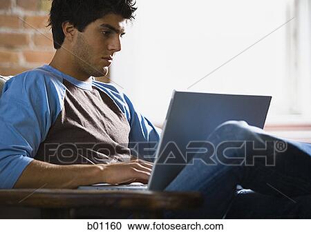 Young man working on a laptop View Large Photo Image Stock Image - Young man working on a laptop. Fotosearch