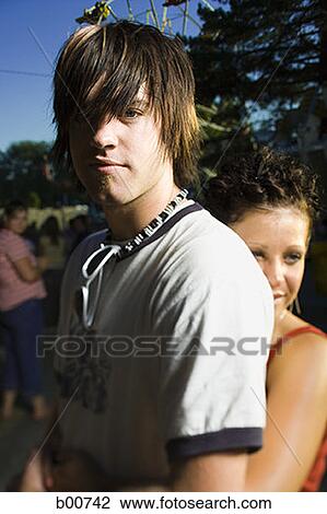 Young woman embracing a young man from behind View Large Photo Image Stock Image - Young woman embracing a young man from behind. Fotosearch