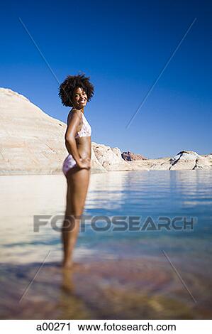 Young woman in a bikini and standing in water View Large Photo Image Stock Image - Young woman in a bikini and standing in water. Fotosearch