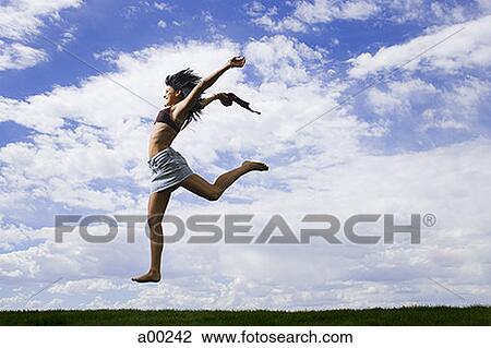 Young woman jumping on grass View Large Photo Image Stock Image - Young woman jumping on grass. Fotosearch