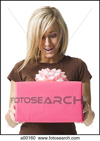 Young woman looking at a gift in her hands View Large Photo Image Stock Image - Young woman looking at a gift in her hands. Fotosearch