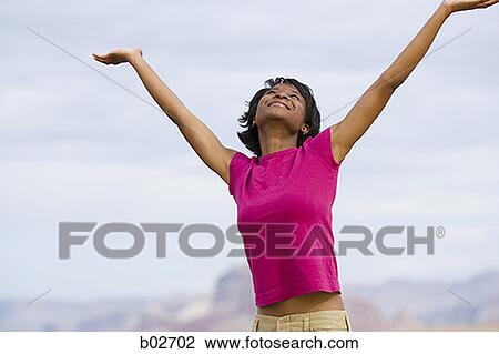 Young woman standing with arm raised View Large Photo Image Stock Image - Young woman standing with arm raised. Fotosearch
