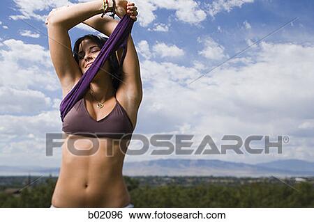 Stock Photograph - Young woman taking her top off. Fotosearch