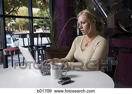 Young woman using a laptop in a café View Large Photo Image Stock Photo - Young woman using a laptop in a café. Fotosearch