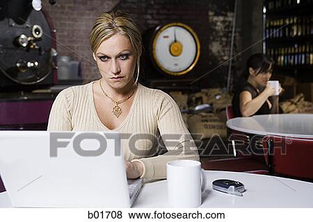 Young woman working on a laptop in a cafe View Large Photo Image Stock Photo - Young woman working on a laptop in a cafe. Fotosearch