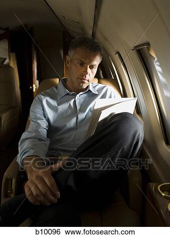 A businessman reading a newspaper in an airplane View Large Photo Image Stock Photograph - A businessman reading a newspaper in an airplane. Fotosearch