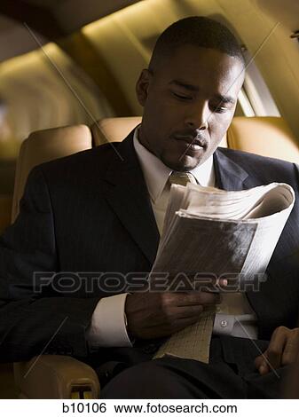 A businessman reading a newspaper in an airplane View Large Photo Image Stock Photograph - A businessman reading a newspaper in an airplane. Fotosearch