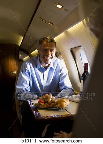 A businessman sitting with a woman in an airplane View Large Photo Image Stock Image - A businessman sitting with a woman in an airplane. Fotosearch