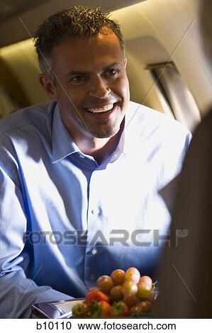 Stock Image - A businessman smiling in an airplane. Fotosearch