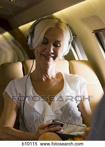 A businesswoman listening to music from an MP3 player in an airplane View Large Photo Image Stock Photography - A businesswoman listening to music from an MP3 player in an airplane. Fotosearch