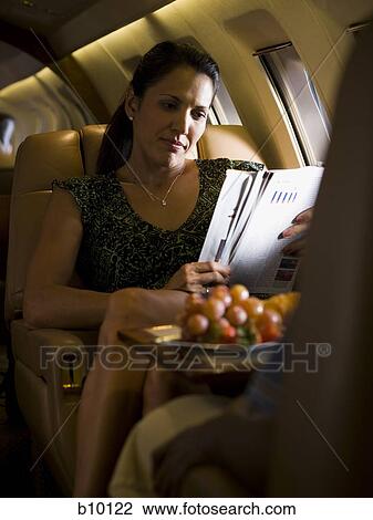 A businesswoman reading a magazine on an airplane View Large Photo Image Stock Image - A businesswoman reading a magazine on an airplane. Fotosearch
