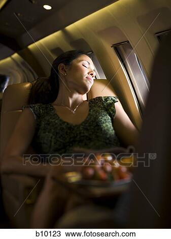 Stock Image - A businesswoman sleeping on an airplane. Fotosearch