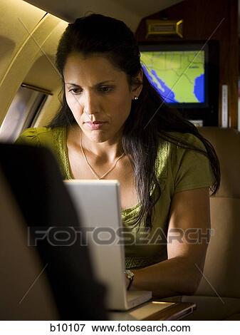 A businesswoman using a laptop in an airplane View Large Photo Image Stock Photo - A businesswoman using a laptop in an airplane. Fotosearch