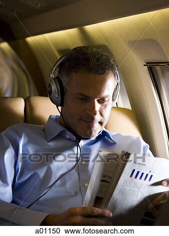 A senior man reading a magazine in an airplane View Large Photo Image Stock Image - A senior man reading a magazine in an airplane. Fotosearch
