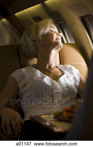 A senior woman sleeping in an airplane View Large Photo Image Stock Photo - A senior woman sleeping in an airplane. Fotosearch