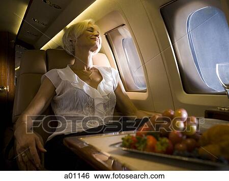 A senior woman sleeping in an airplane View Large Photo Image Stock Photograph - A senior woman sleeping in an airplane. Fotosearch