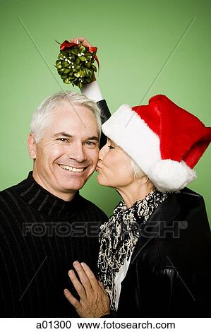 A woman holds mistletoe over a man's head while kissing him on the cheek View Large Photo Image Stock Image - A woman holds mistletoe over a man's head while kissing him on the cheek. Fotosearch