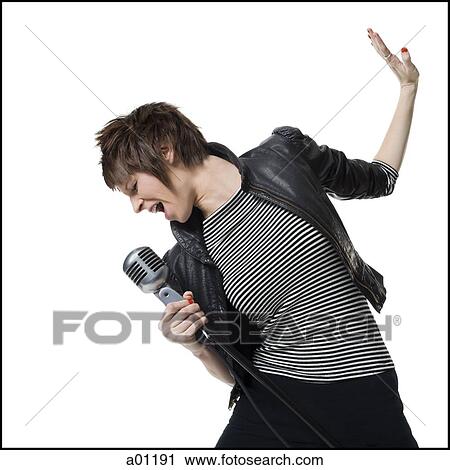 A young woman singing into a microphone View Large Photo Image Stock Image - A young woman singing into a microphone. Fotosearch