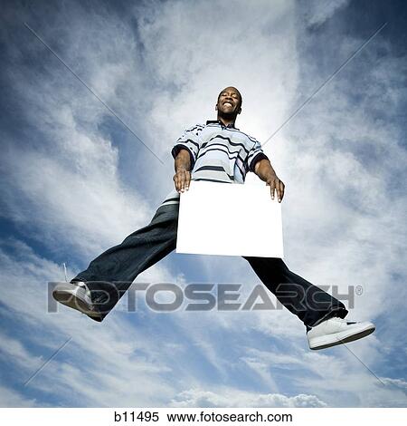 African American man jumping and holding a blank sign View Large Photo Image Stock Photography - African American man jumping and holding a blank sign. Fotosearch