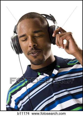 Picture - African American man listening to music on headphones. Fotosearch