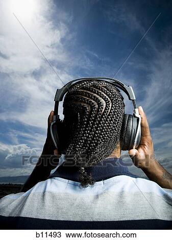 Stock Image - African American man listening to music on headphones. Fotosearch