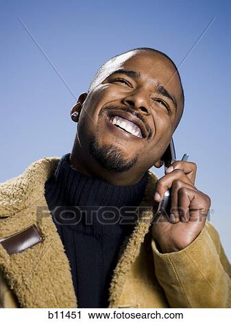 Stock Image - African American man smiling and talking on cell phone. Fotosearch