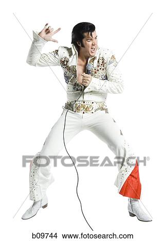 An Elvis impersonator singing into a microphone and jumping View Large Photo Image Picture - An Elvis impersonator singing into a microphone and jumping. Fotosearch