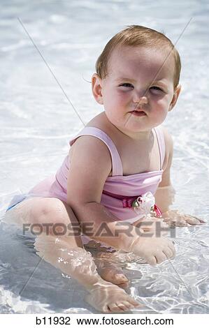 Stock Image - Baby girl in wading pool. Fotosearch