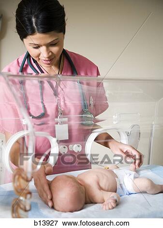 Stock Photo - Baby in incubator with female nurse. Fotosearch