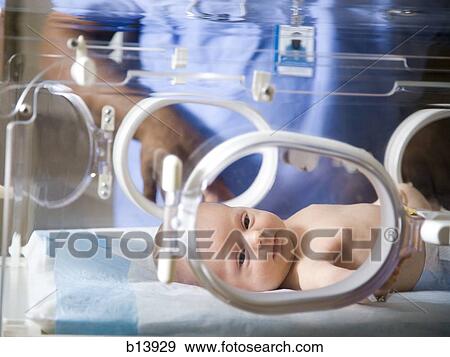 Stock Photo - Baby in incubator with man in uniform. Fotosearch