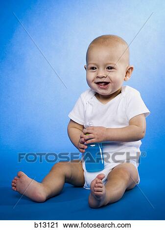 Stock Image - Baby sitting with bottle. Fotosearch