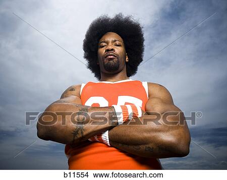 Picture - Basketball player with an afro in orange uniform. Fotosearch