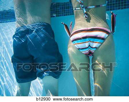 Stock Image - Behind view of couple underwater. Fotosearch