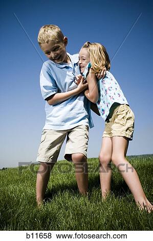 Boy and girl playing on a hill View Large Photo Image Stock Photo - Boy and girl playing on a hill. Fotosearch