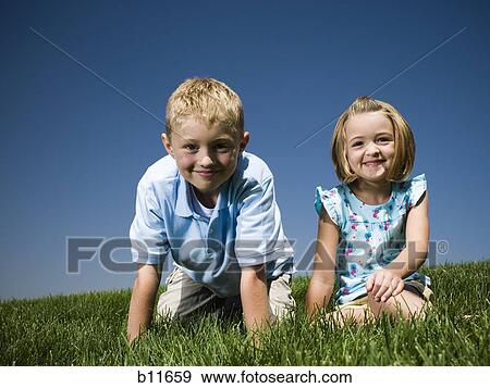 Boy and girl sitting on a hill View Large Photo Image Stock Photo - Boy and girl sitting on a hill. Fotosearch